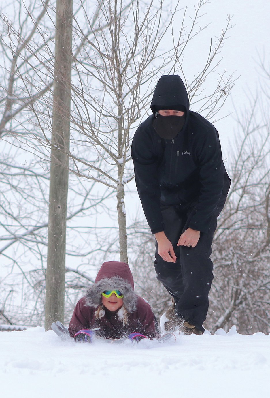 Mabel Hoar, 11, gets a push from dad Panch Hoar to get the best run down a snow-covered hillside at Milligan Park.